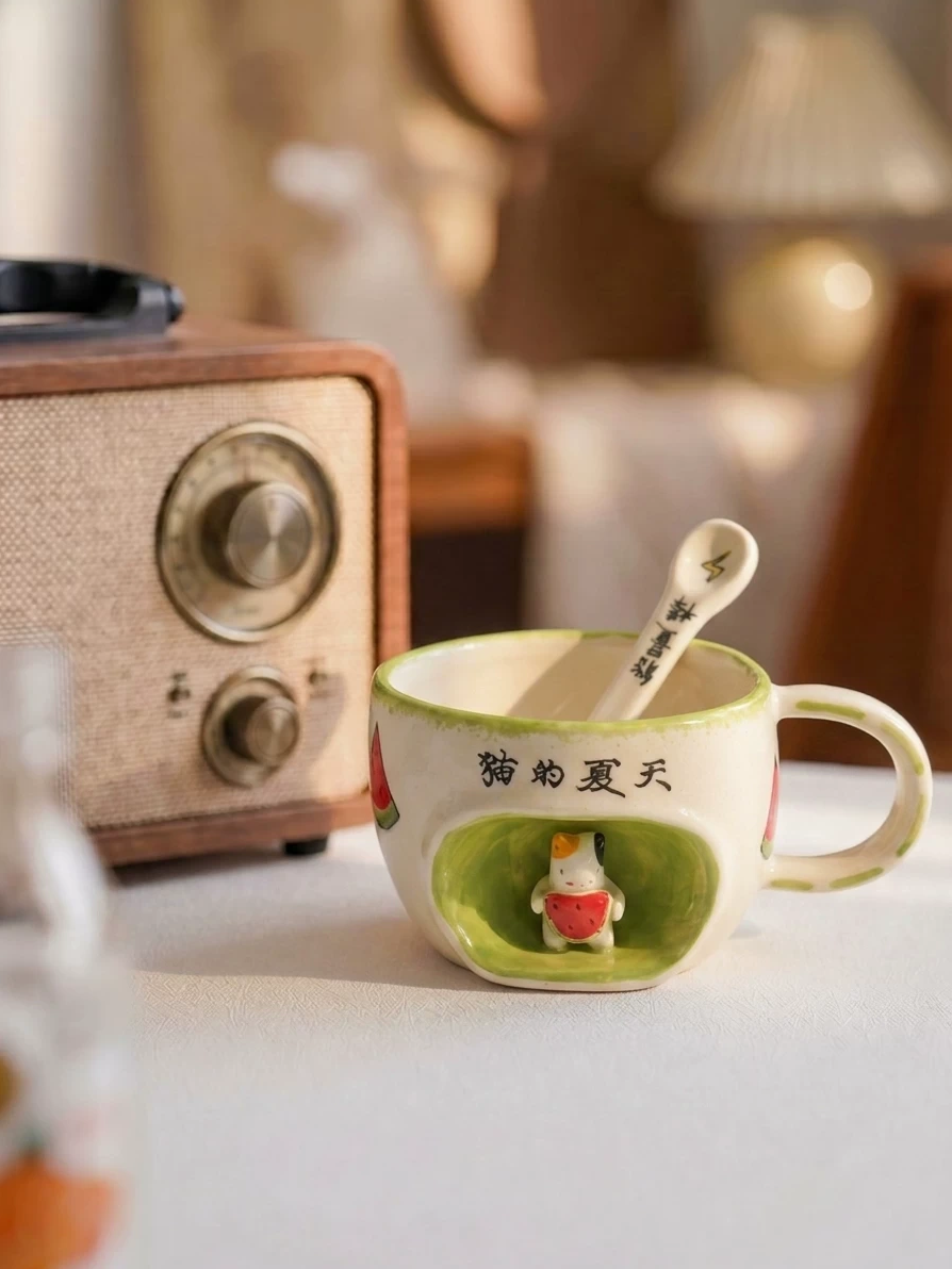 Cat’s Summer ceramic mug with a sculptural cat holding a watermelon in a green recessed scene