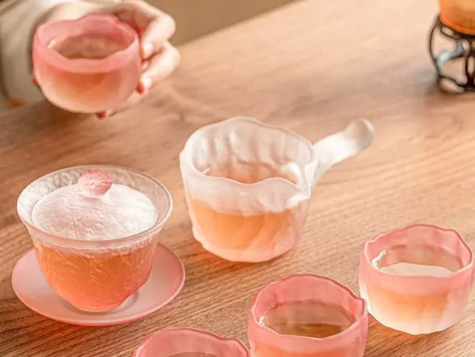 Gradient pink glass gaiwan in an everyday tea-table scene with cups and a sharing pitcher