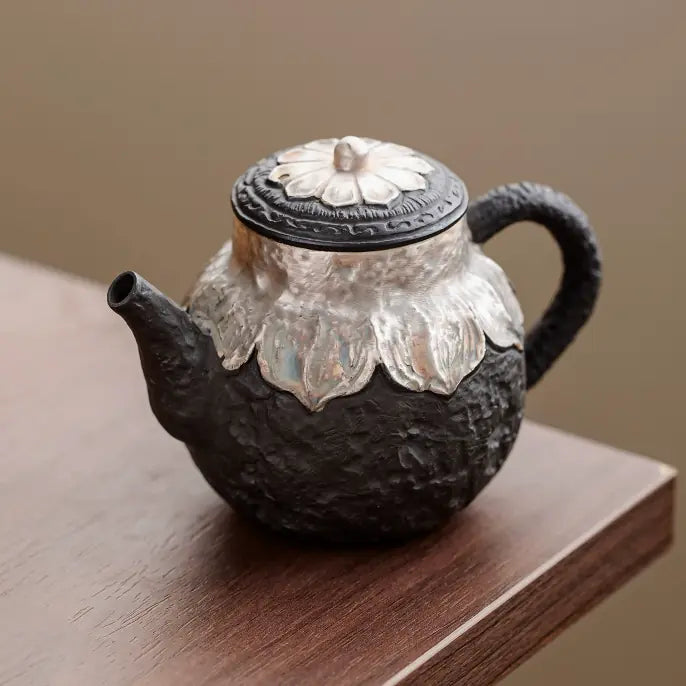 Black zisha silver-finished lotus teapot on a wooden table
