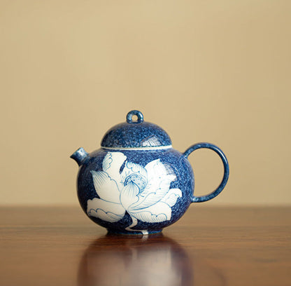 Chinese lotus ceramic teapot with deep blue mottled glaze on a wooden table
