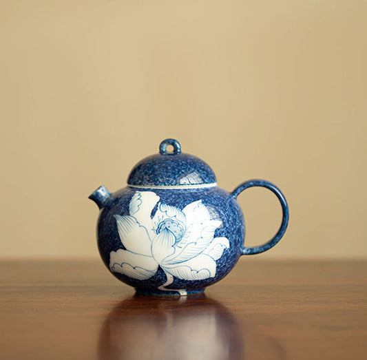 Chinese lotus ceramic teapot with deep blue mottled glaze on a wooden table
