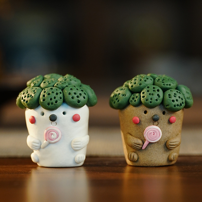 Gray-brown and white hand-pinched broccoli tea pets displayed together on a wooden table