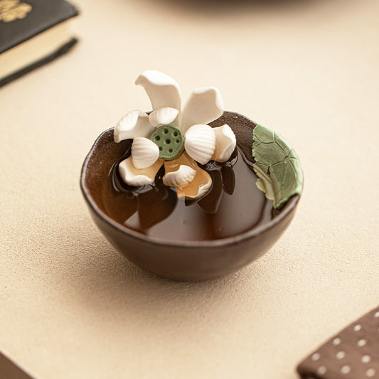 Handmade wood-fired lotus ceramic tea cup on a warm neutral tabletop