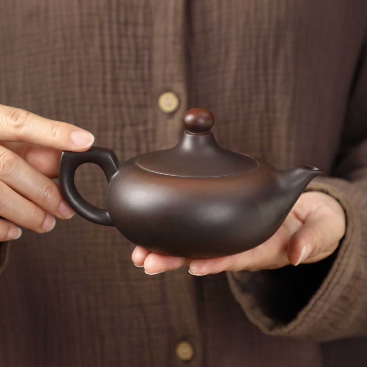 Handmade matte Yixing Zisha Fengming teapot held in both hands