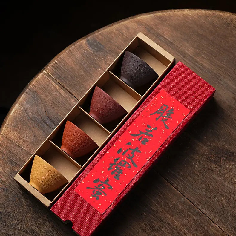 Overhead view of four Heart Sutra zisha tea cups in a red divided gift box