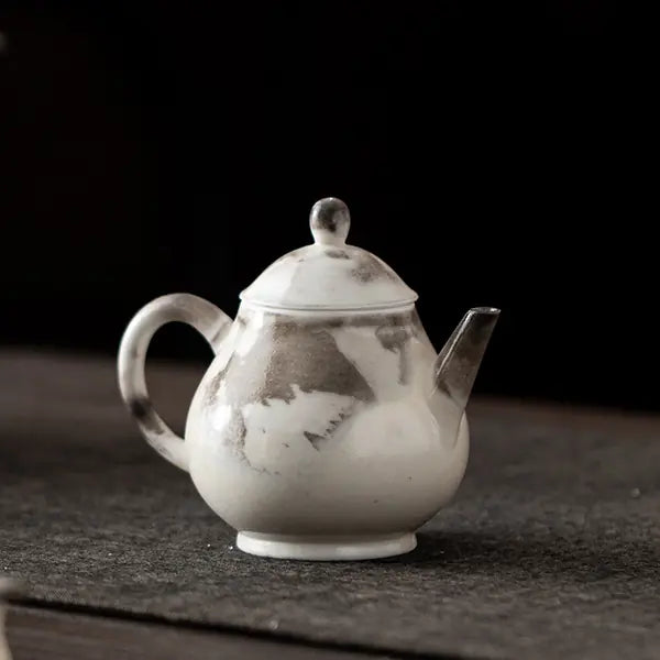 Handmade Chinese ink-wash Ruyi ceramic teapot on a dark tea mat