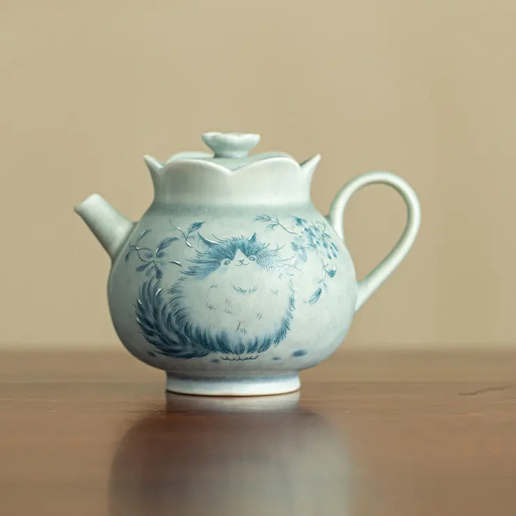 Front view of a pale green Jingdezhen ceramic teapot with a blue cat motif
