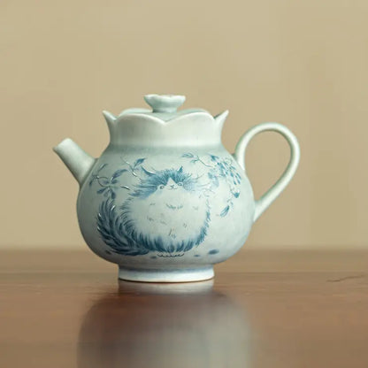 Front view of a pale green Jingdezhen ceramic teapot with a blue cat motif

