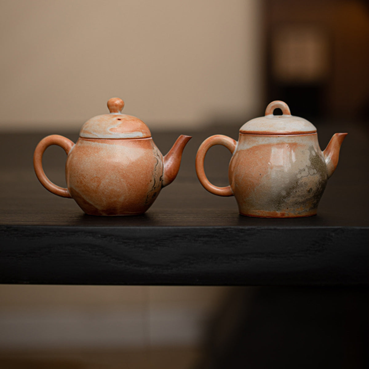 Two handmade Shino-style ceramic teapots in Liting and Liqin shapes on a dark table