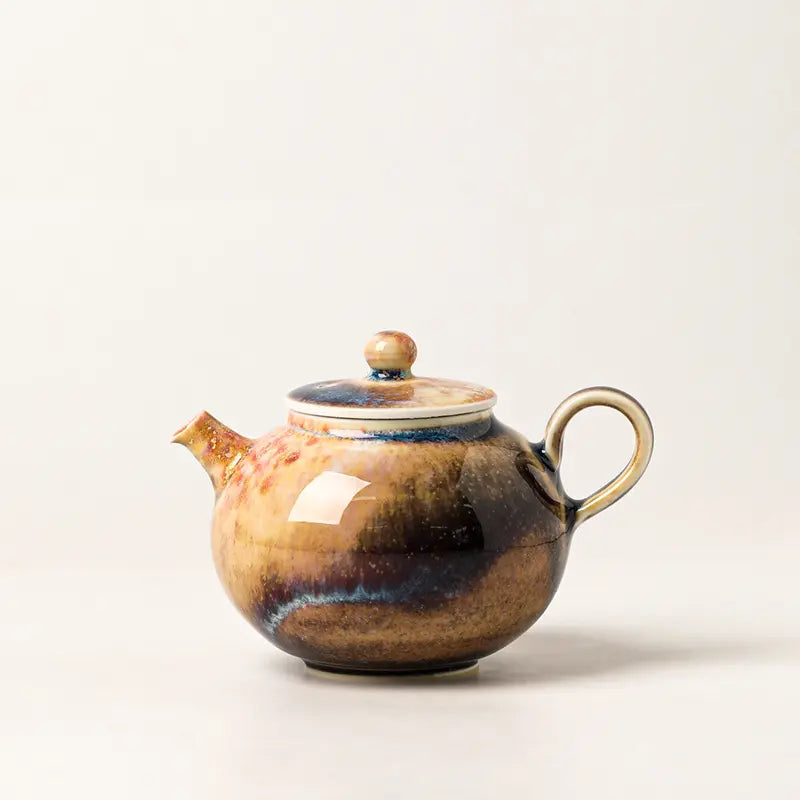Front view of a handmade Jingdezhen wood-fired ash glaze teapot on a warm ivory background