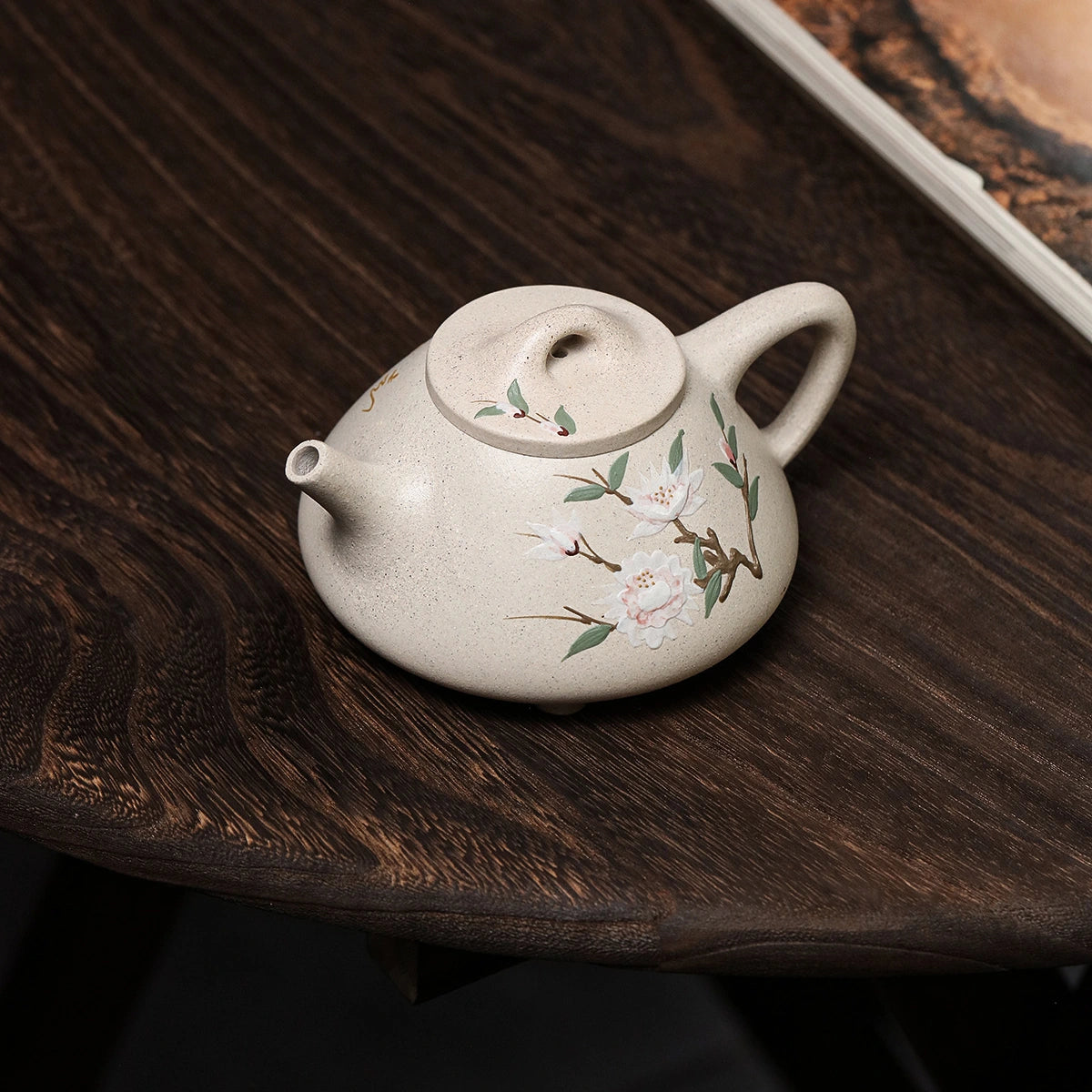 White duanni Shi Piao teapot with floral slip painting on a dark wood table