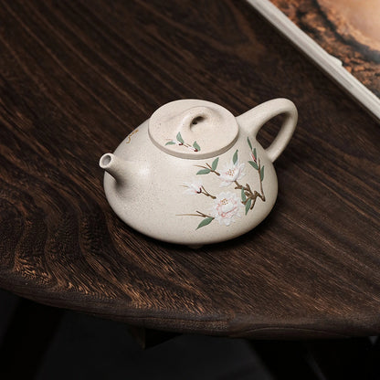 White duanni Shi Piao teapot with floral slip painting on a dark wood table