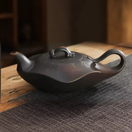 Yixing zisha teapot with lotus and calligraphy carving on a warm wooden tea table