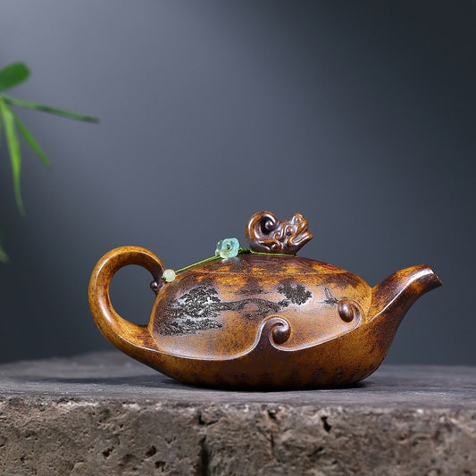 Yixing zisha wood-fired teapot with carved landscape, dragon lid knob, and green bead on a stone display

