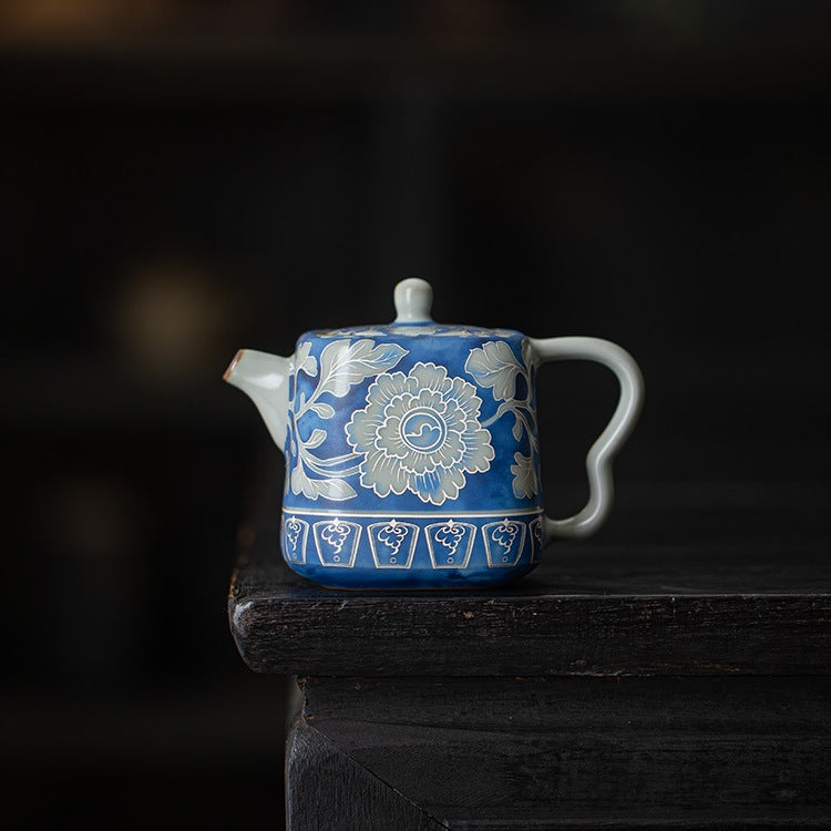 Front view of a blue peony crackle glaze teapot in a dark studio setting
