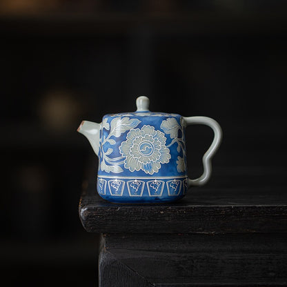 Front view of a blue peony crackle glaze teapot in a dark studio setting

