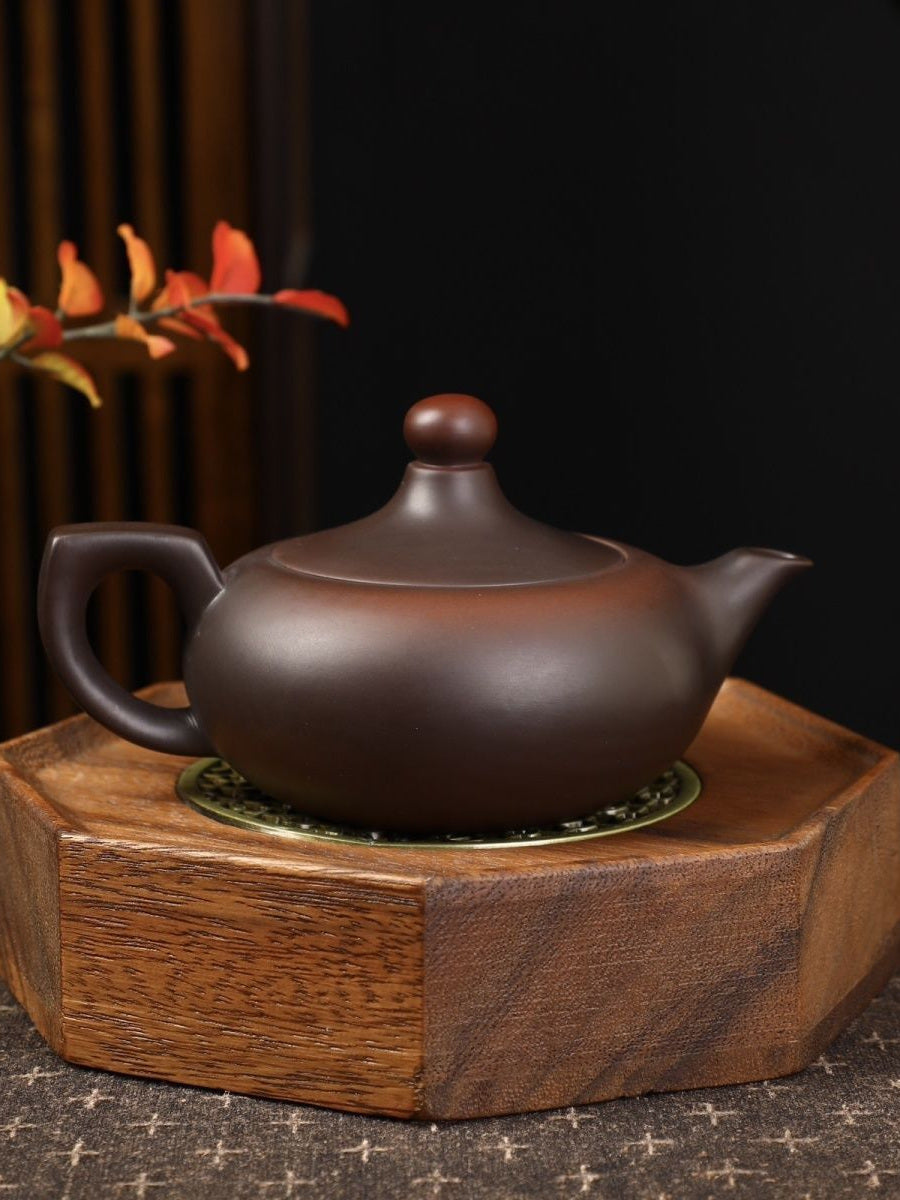 Deep brown Fengming Zisha teapot displayed on a wooden stand