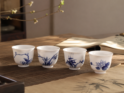 Four Gentlemen blue-and-white porcelain tea cups arranged on a quiet tea table beside an open book
