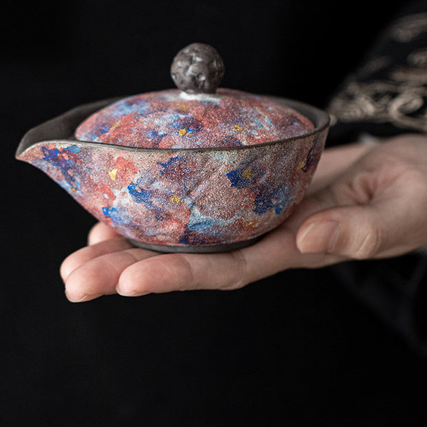 Hand holding a compact galaxy glaze handleless ceramic teapot
