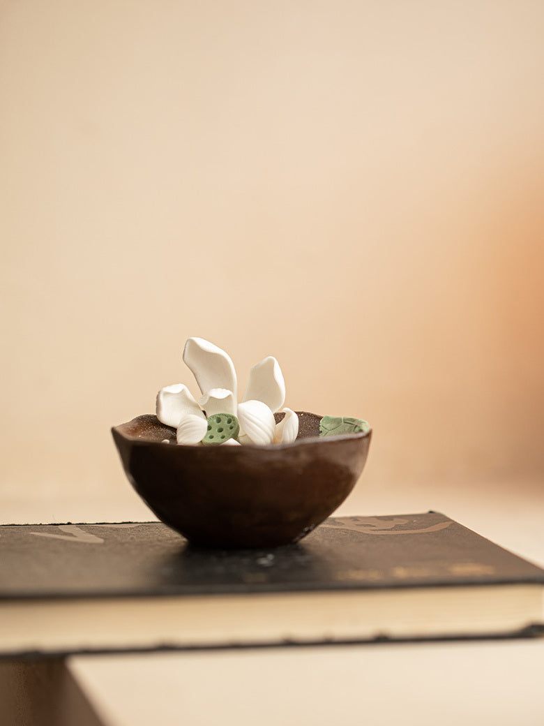 Side view of a handmade lotus ceramic tea cup displayed on a book