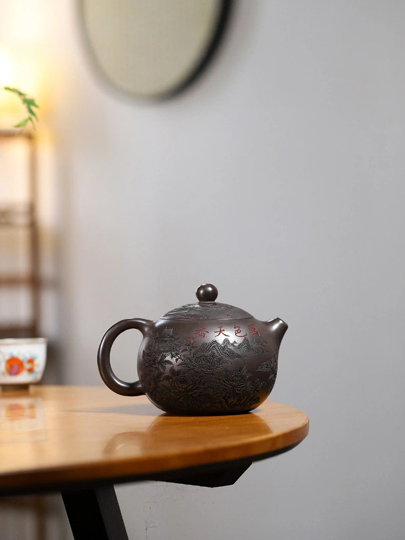 Reverse view of a dark brown Yixing zisha teapot with carved peonies and a red Chinese inscription
