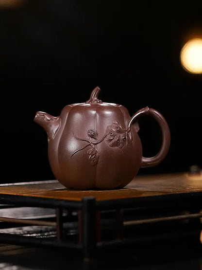 Front view of a handcrafted pumpkin-shaped zisha teapot with a vine-inspired handle and spout