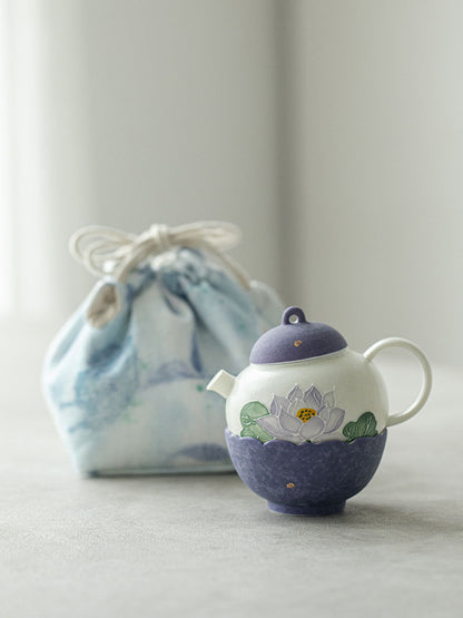 Hand-painted purple lotus ceramic teapot displayed beside its blue drawstring travel pouch