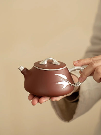 Handmade Yixing zisha teapot held in both hands showing its compact rounded form