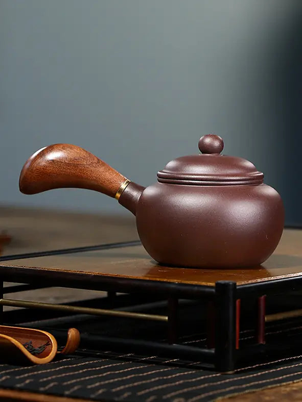 Side profile of a brown Yixing zisha teapot with a curved wooden handle