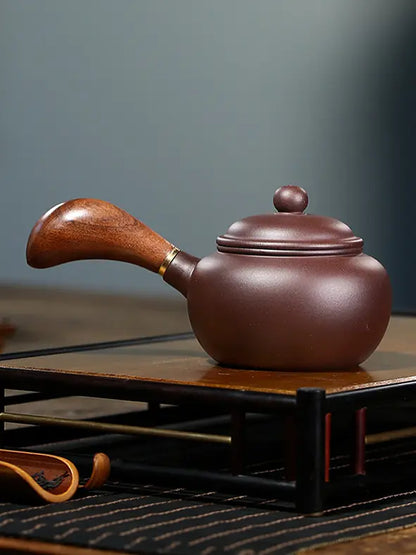 Side profile of a brown Yixing zisha teapot with a curved wooden handle