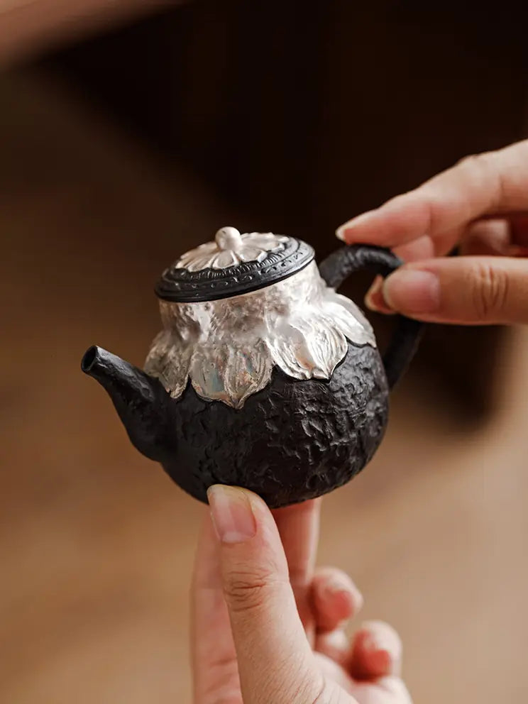 Black zisha teapot balanced in hand to show its compact size
