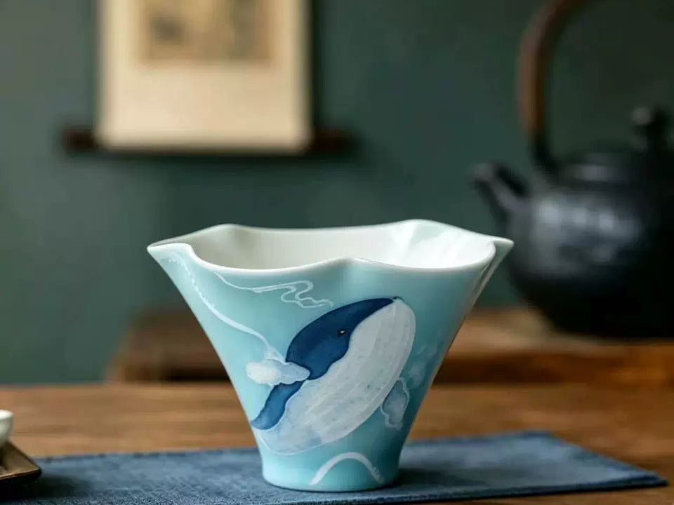 Hand-painted blue whale ceramic tea cup displayed on a wooden tea table