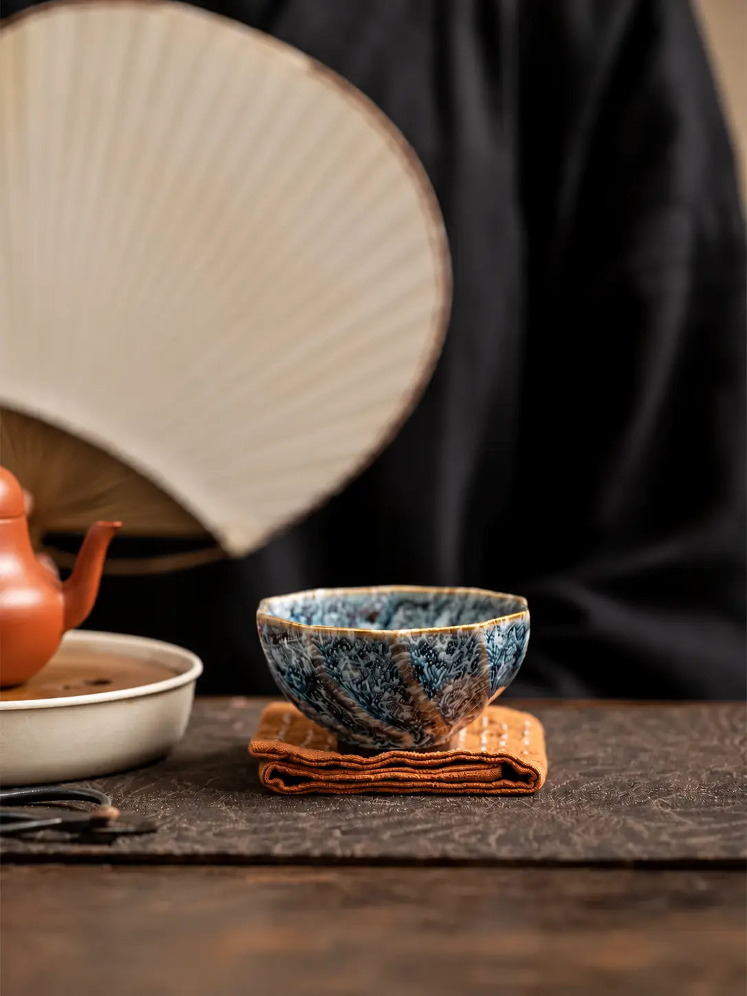 Blue-and-white faceted ceramic tea cup resting on a folded brown tea cloth