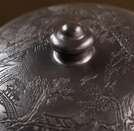 Close-up of the carved landscape design across the lid of the Fengming zisha teapot
