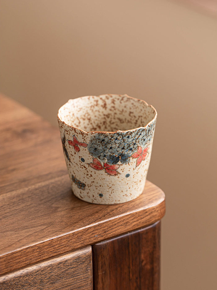 Angled top view of the handmade flower-rim ceramic coffee cup on a rounded wooden table