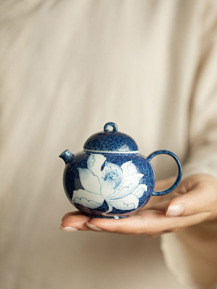Hand holding a compact blue and white lotus ceramic teapot
