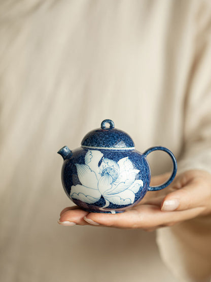 Hand holding a compact blue and white lotus ceramic teapot

