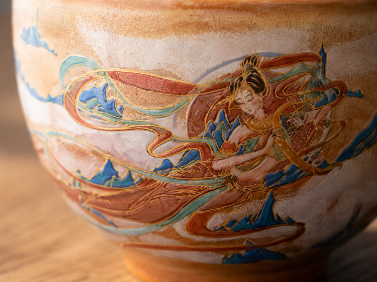 Close-up of the hand-painted celestial figure and flowing ribbons on the ceramic tea cup