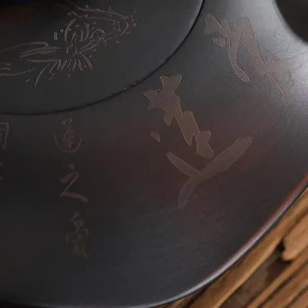 Close-up of lotus and Chinese calligraphy carving on the deep brown zisha teapot