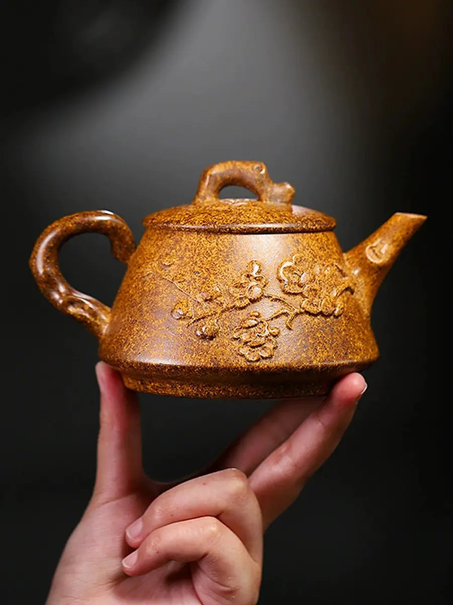 Front view of the golden-brown Shi Piao zisha teapot held by hand