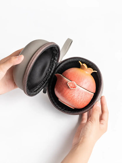 Open gray carrying case holding the nested pomegranate ceramic travel tea set
