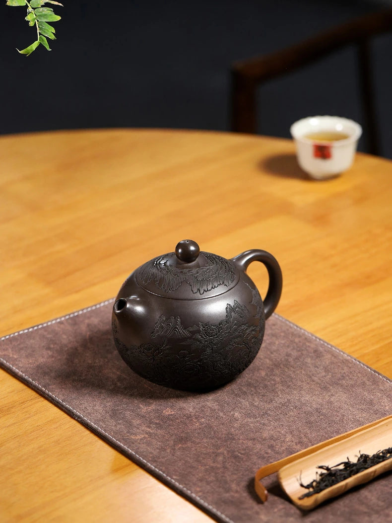 Carved Yixing zisha Xishi teapot displayed on a tea mat beside loose tea and a tea scoop