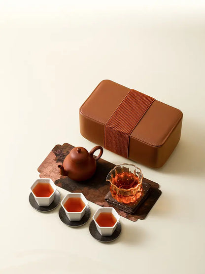 Zisha teapot, glass fairness pitcher, and three tasting cups beside the brown storage case
