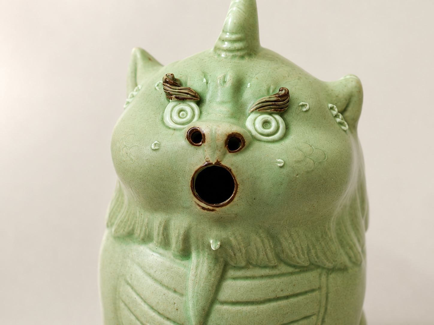 Close-up of the Suanni incense burner face and pale green glaze details
