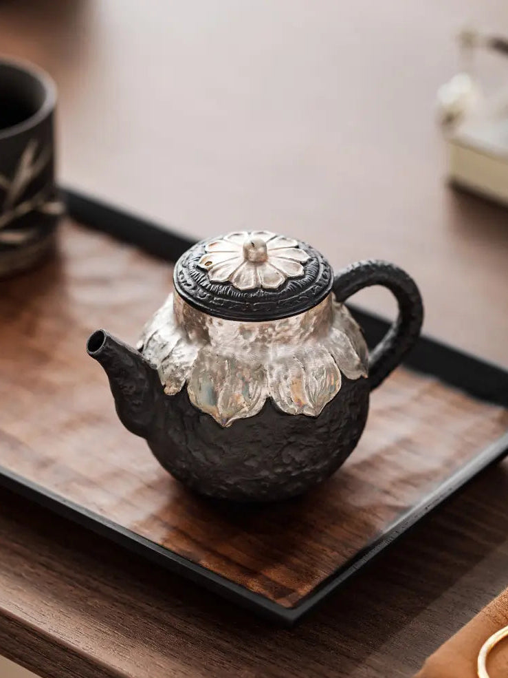 Black zisha silver-finished teapot displayed on a wooden tea tray
