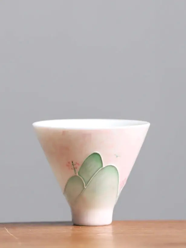 Pink and green hand-painted landscape ceramic teacup on a neutral studio background