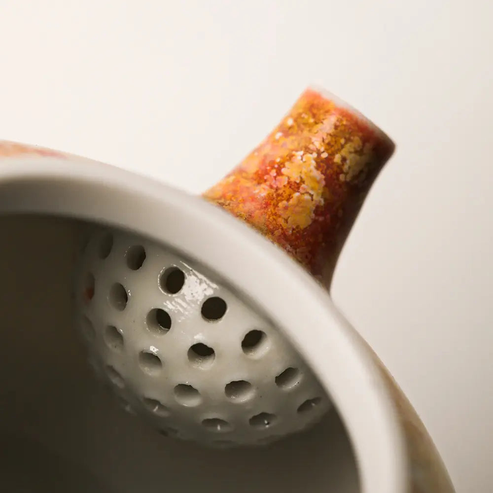 Close-up of the built-in multi-hole ceramic strainer inside the wood-fired teapot