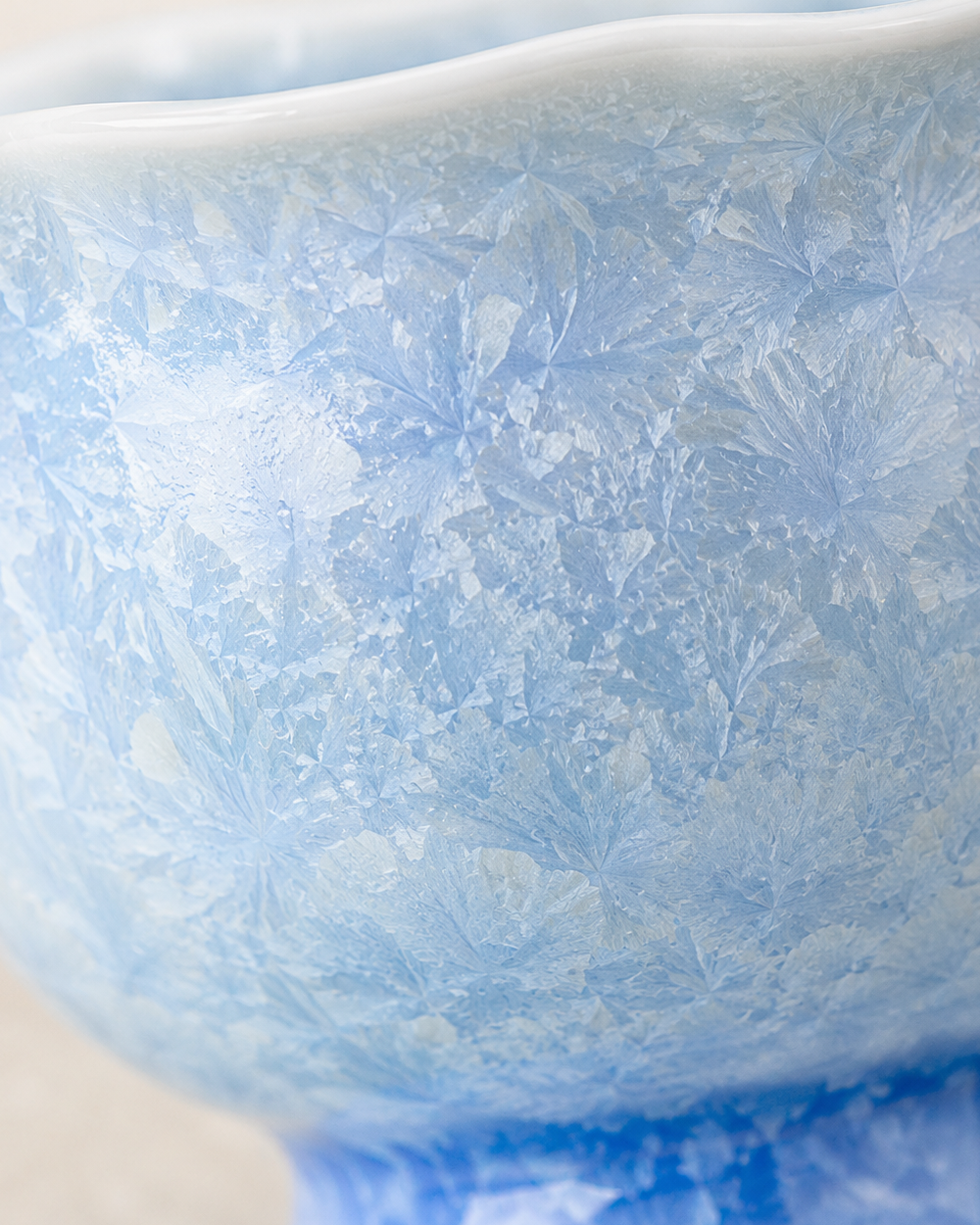 Macro detail of frost-like crystalline patterns on the pale blue ceramic glaze