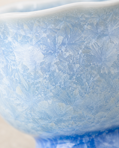 Macro detail of frost-like crystalline patterns on the pale blue ceramic glaze
