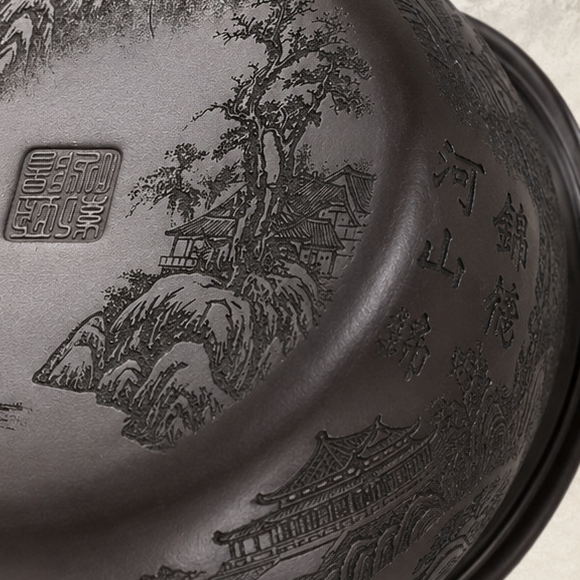 Close-up of the landscape carving, seal mark, and Chinese characters on the base of the Fengming zisha teapot
